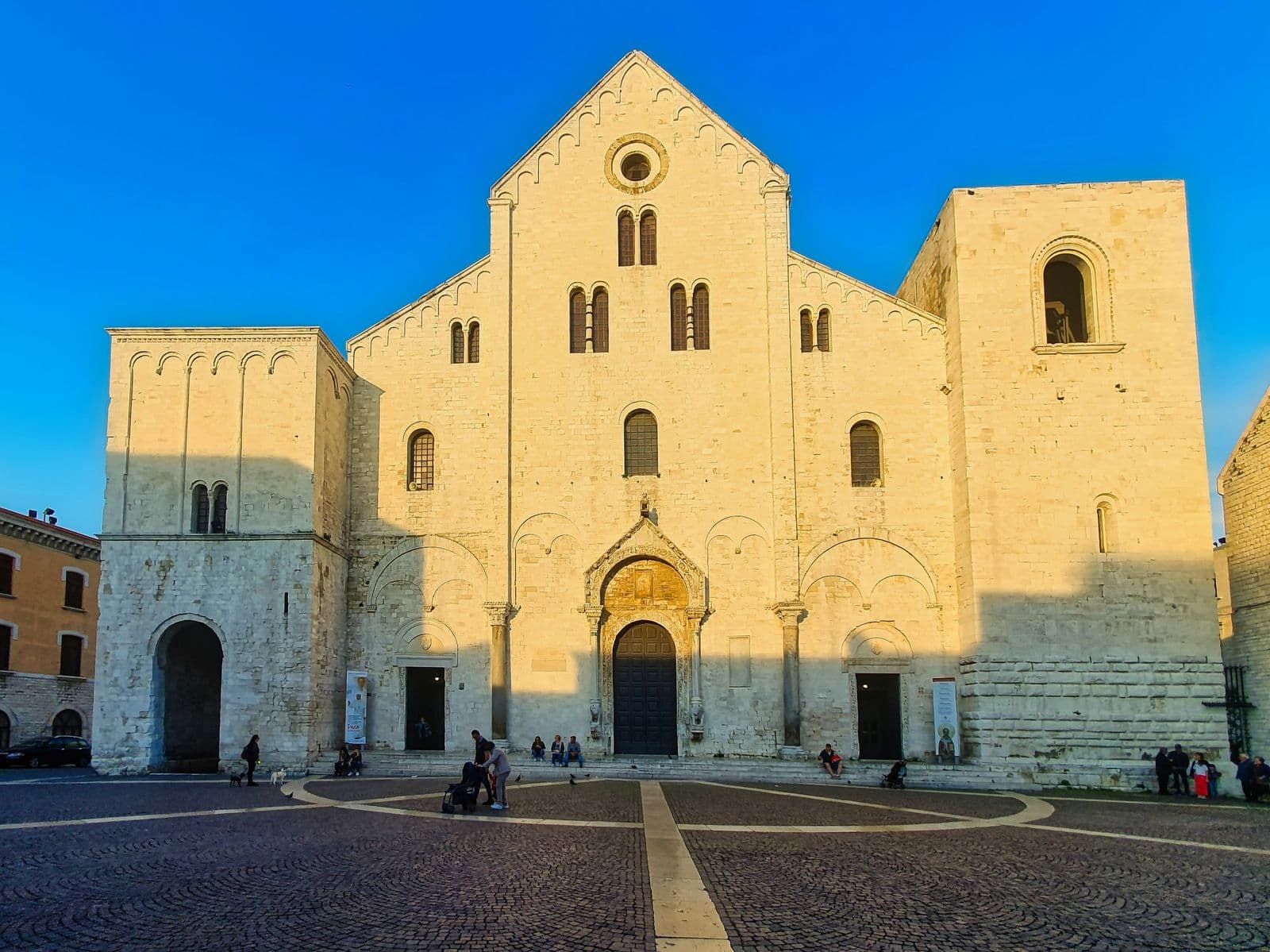 The facade of the Basilica of San Nicola in Bari, lit gold by low sun